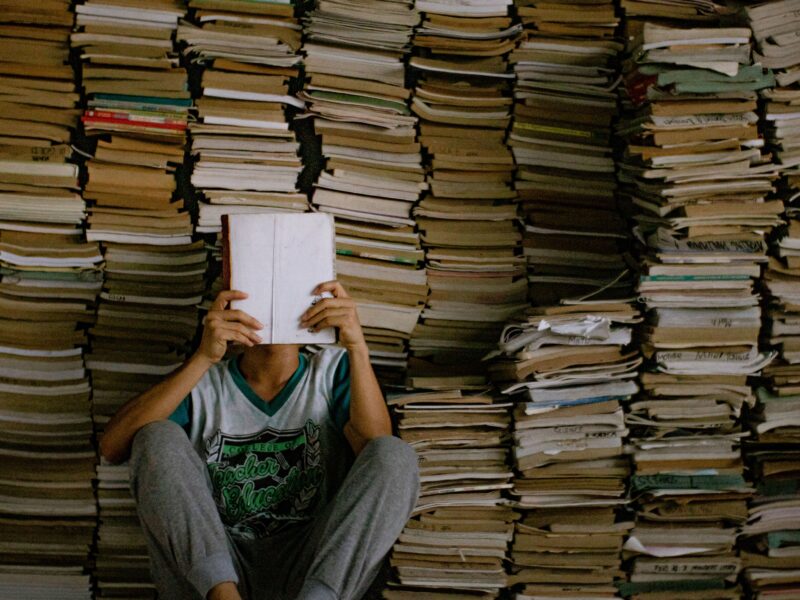 A person reading a book surrounded by tons of books - one percent readers